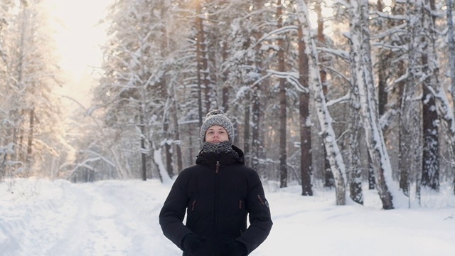 少年在冬天编织帽子和围巾走过冬天的雪林。视频素材