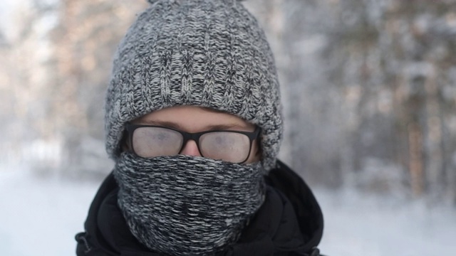 冬天雪地里戴着雾蒙蒙眼镜的人。编织帽子和围巾。视频素材