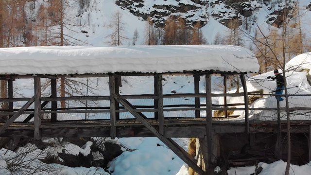 在意大利阿尔卑斯山滑雪旅游:肩上扛着滑雪板过桥视频素材