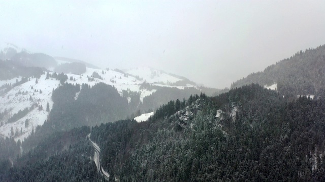 高空鸟瞰图飞行在一个冬天的高山山脊与道路在大雪视频素材