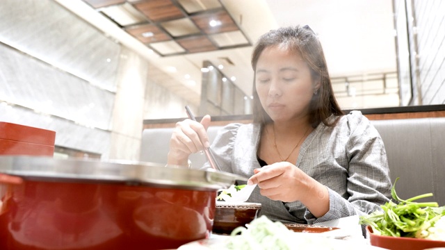 年轻美丽的亚洲女人在餐厅吃涮锅sukiyaki火锅的场景，假期周末的概念，亚洲女人的生活方式视频素材