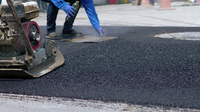 工人使用地面压路机进行道路施工视频素材