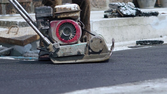 工人使用地面压路机进行道路施工视频素材