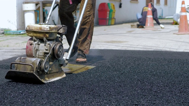 工人使用地面压路机进行道路施工视频素材