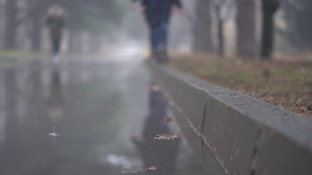 秋雨过后的小巷在秋天的人行道上泛起水坑。视频素材