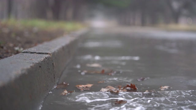 落寞的秋雨后巷，流水淹没了沥青路。视频素材