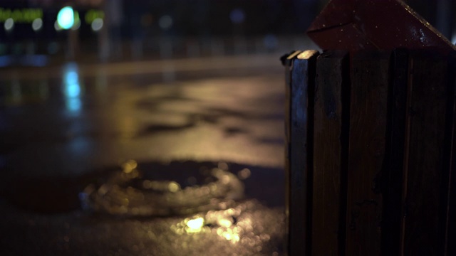 雨夜城市街道，街灯映照在雨后人行道上的水坑视频素材