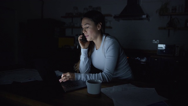 专注于商务女性工作在笔记本电脑在家里在电话交谈视频素材