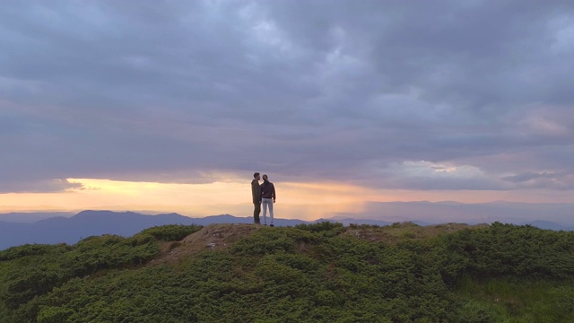 一个男人和一个女人站在山顶上在夕阳的背景下视频素材