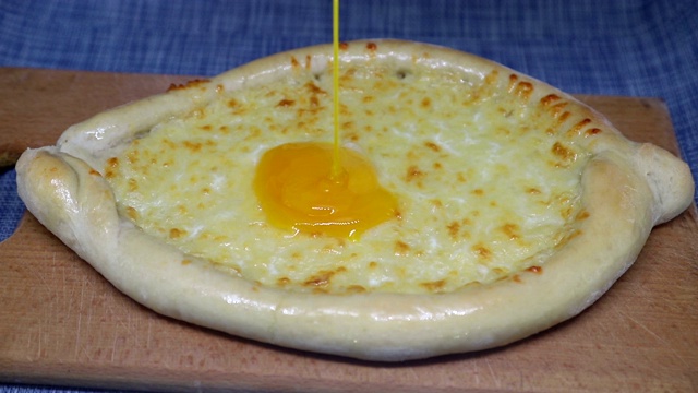 鸡蛋倒在khachapuri(格鲁吉亚奶酪糕点)上视频素材