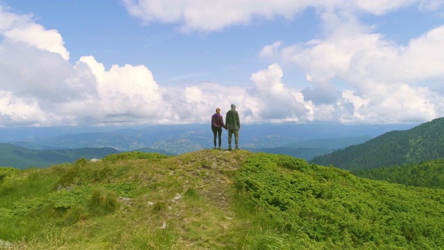 以一对站立的夫妇为背景，在群山之上飞行视频素材