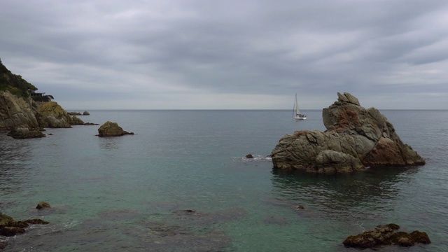 夕阳下，一只孤独的小船在灰色平静的海面上航行。神秘的风景。视频素材