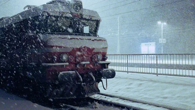 在冬天的夜晚，火车火车头下着雪花。铁路、铁路运输。火车在车站，冬天的雪夜。视频下载