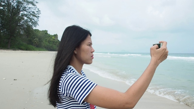 女人在海滩上用手机拍照视频素材