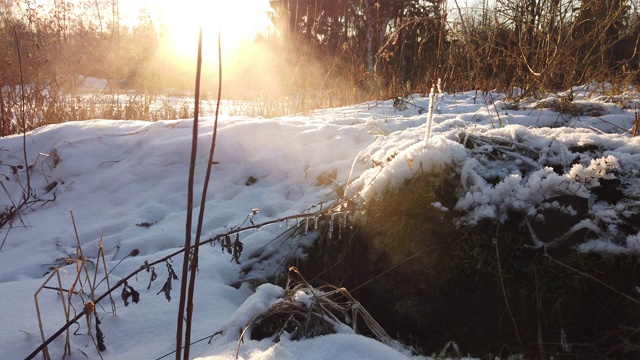 日落时，蒸汽从白雪覆盖的冬季地面下涌出。视频素材