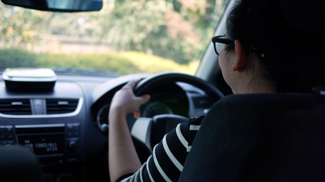 一个年轻女子开着一辆车，打开收音机，在阳光明媚的乡村街道上跳舞。视频素材