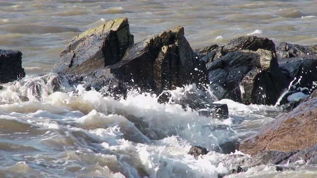 晴朗多风的一天，苏格兰海滩上的海浪拍打着岩石视频素材