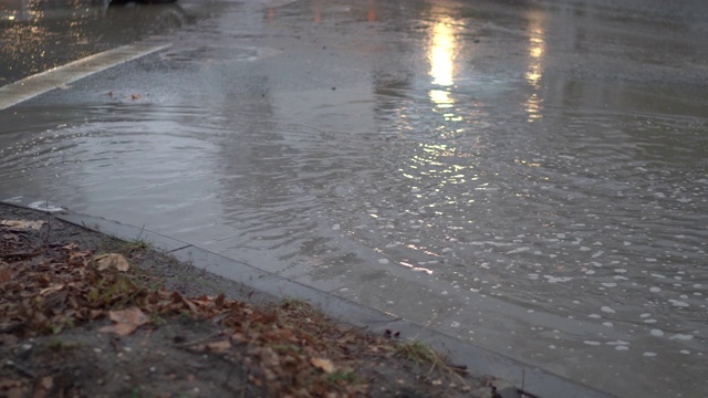 在秋天的雨天，城市交通在潮湿的道路上行驶。路上有个大水坑。视频素材