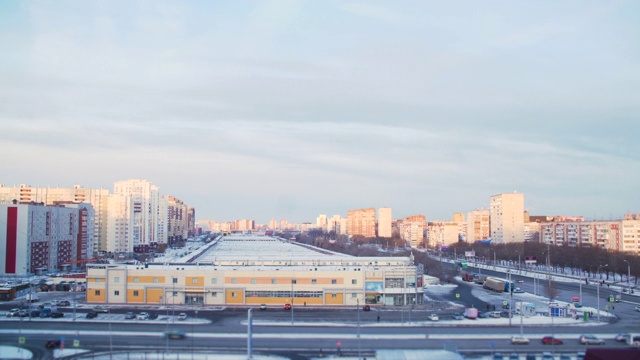 时光流逝美丽的日落和彩色的天空在现代城市。早晨日落时，城市上空是蓝色和粉红色的天空。冬季城市景观时光流逝，汽车运动。城市汽车在附近运动。视频素材