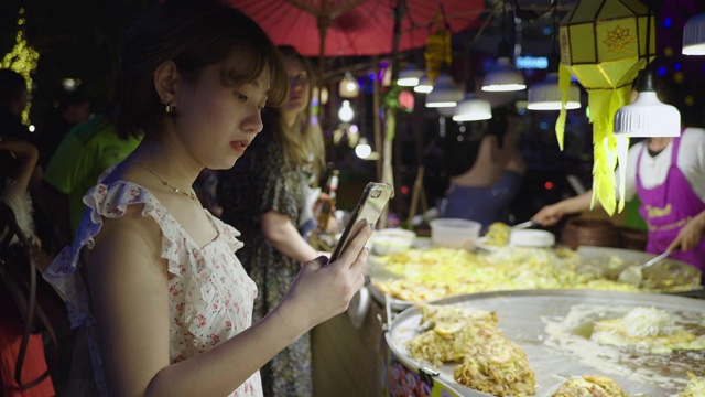 亚洲女人用手机拍照泰国煎贻贝煎饼(Hoi Tod)在夜市视频素材