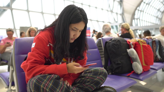 一名女子坐在候机区使用手机视频素材