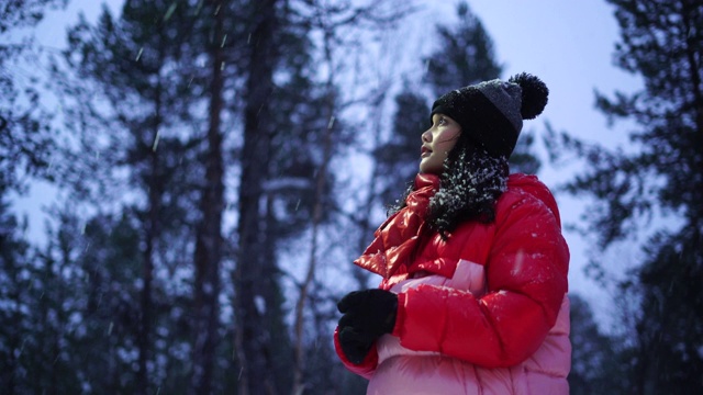 年轻女子看着雪花飘落视频素材