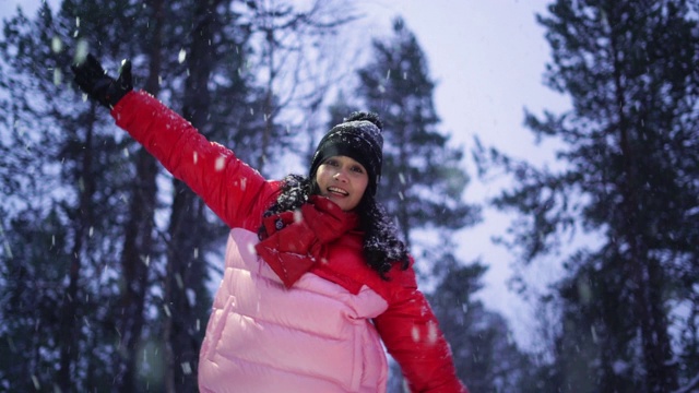 快乐的年轻女子在雪花下玩耍视频素材