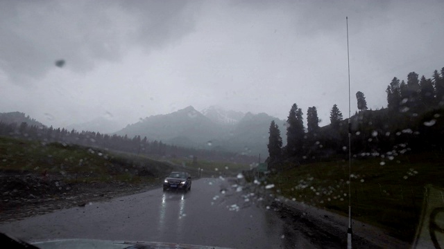 汽车在雨天行驶在山路上，新疆，中国。视频素材