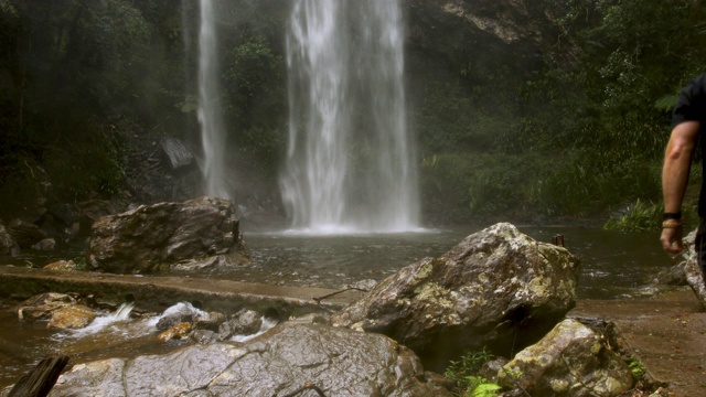 澳大利亚热带雨林的徒步旅行者停下来拍摄大瀑布视频素材