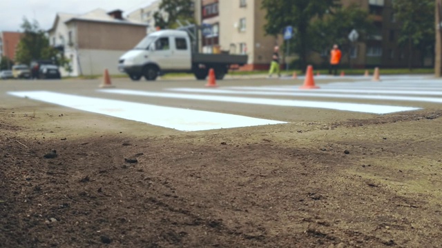 在城市街道的十字路口，工人们用油漆在人行道上画上斑马线视频素材