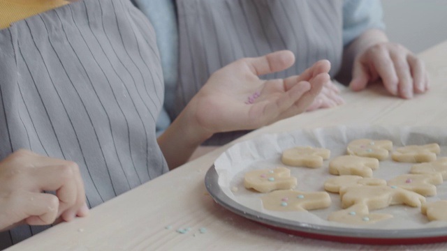 快乐的女孩和奶奶在烘烤前装饰复活节饼干视频素材