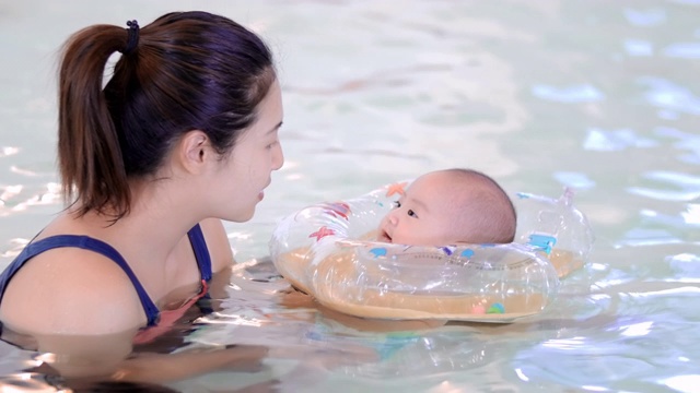 可爱的宝宝和他的妈妈在游泳池里视频素材