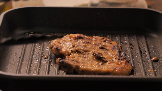 近景拍摄烹饪和烤猪肉牛排在热锅，选择对焦浅景深视频素材