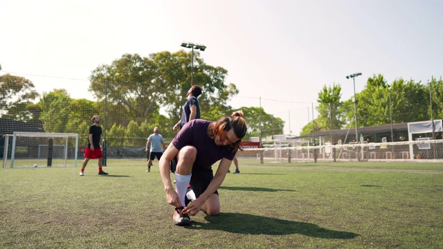 在足球场上系鞋带的男人视频素材