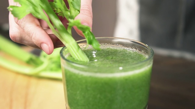 女用芹菜杆搅拌绿色奶昔，慢动作。健康食品的概念。视频素材