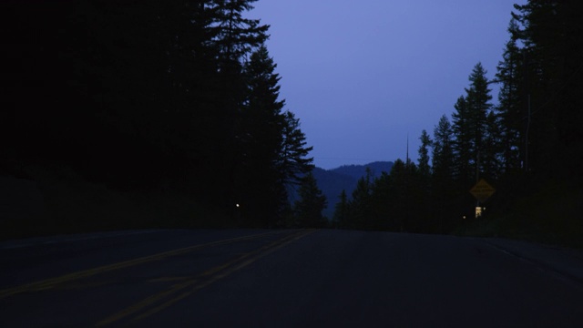 车辆的观点，沿着一个树木排列的道路在山区晚上视频素材