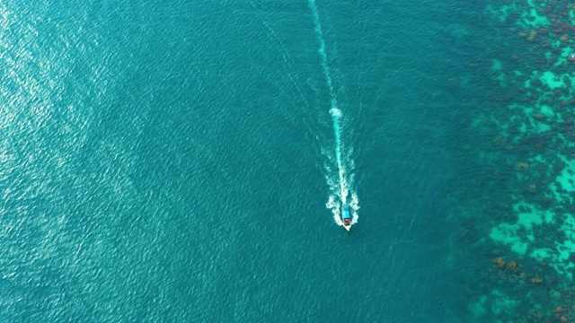 鸟瞰图上的长尾船漂浮在清澈的水沿沙滩在泰国。夏季鸟瞰图镜头4K。视频素材