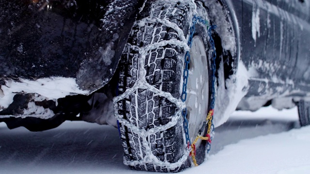 观点。冬天的轮胎在下雪的路上行驶。给轮胎上链子。冬天的道路安全。视频素材