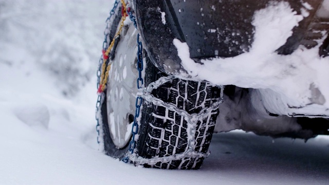 观点。冬天的轮胎在下雪的路上行驶。给轮胎上链子。冬天的道路安全。视频素材