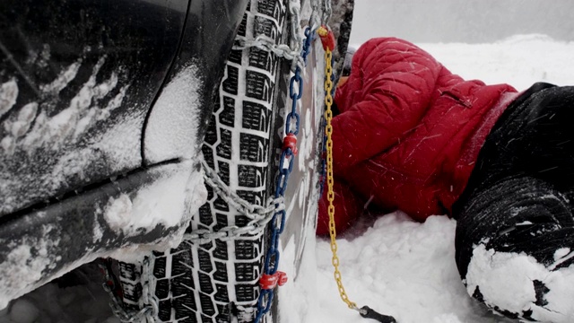 观点。冬天的轮胎在下雪的路上行驶。英俊活跃的老男人给轮胎上链子。冬天的道路安全。视频素材