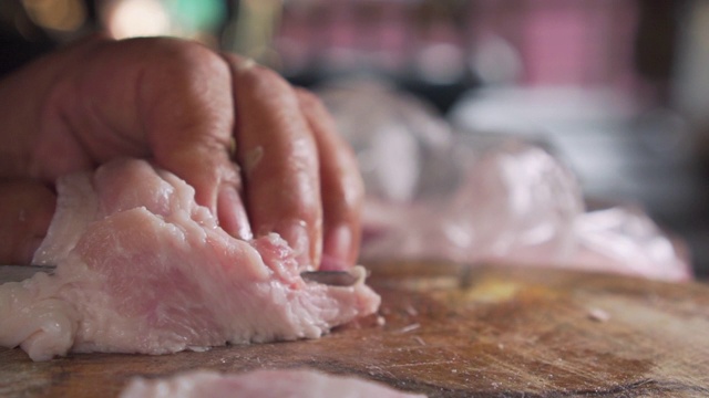 老太太用刀切生猪肉。准备做饭。泰国菜。视频素材