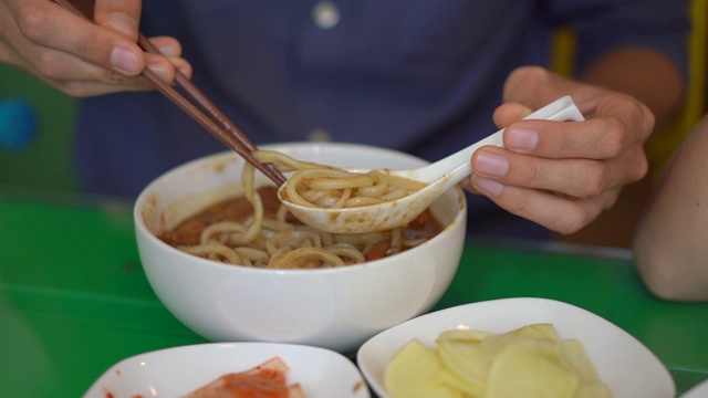 一个年轻人在韩国餐馆吃传统的韩国面乌冬视频素材