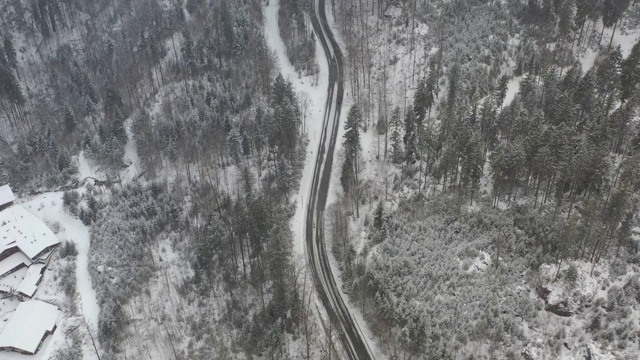 在大雪中，一辆汽车在弯弯曲曲的冬季道路上行驶的鸟瞰图视频素材