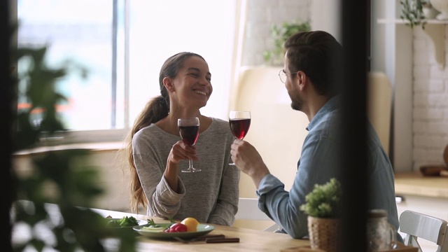 年轻的已婚夫妇喝着红酒碰杯。视频素材