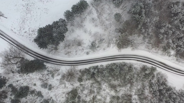 从高空跟踪一辆汽车，它在大雪中行驶在一条蜿蜒的冬日道路上视频素材