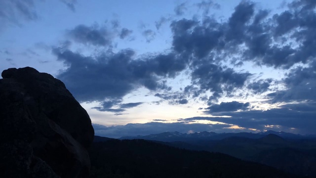 日落时，当月亮落下时，戏剧性的红色、黄色和橙色的云流过落基山脉，时间流逝视频素材