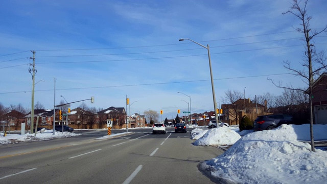 在城市街道十字路口等待红灯右转的汽车。冬季有雪城市道路的车辆病人与右转。视频素材