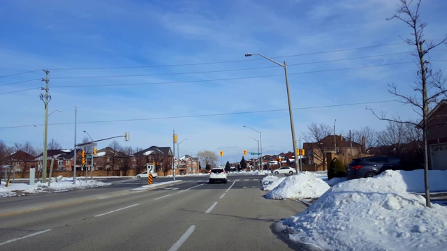 冬天，在城市街道十字路口，汽车在红灯前耐心等待。城市道路上车流和积雪的车辆病人。视频素材