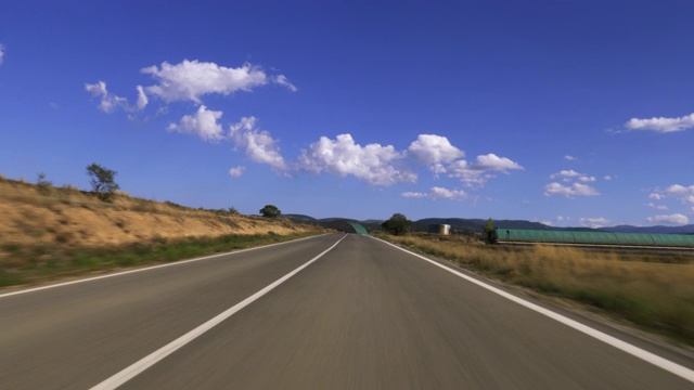 前面的汽车在空旷的高速公路上飞驰，群山映衬着蓝天白云视频素材