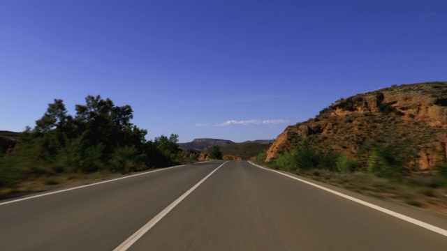 前面的汽车在空旷的高速公路上飞驰，群山映衬着蓝天白云视频素材